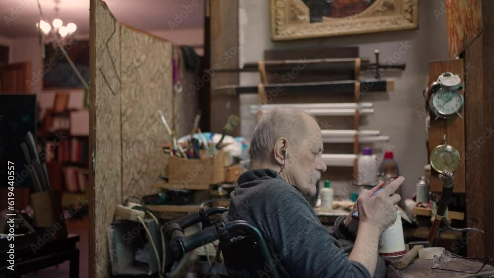 An old craftsman in a wheelchair rests in his workshop An old craftsman in a wheelchair rests in his workshop