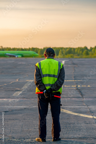 Rear view of a male peron worker standing on the airport runway during sunset
