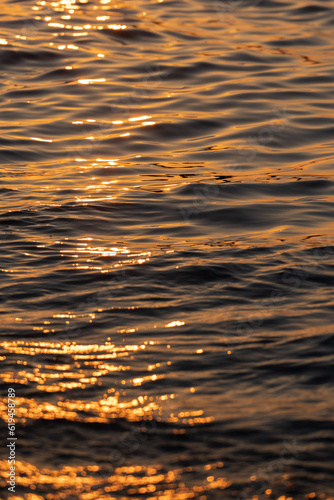 Ripple sea ocean water surface with golden sunset light. Sea waves close up