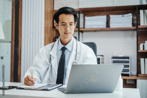 Asian medical doctors specialist in white lab coats , research or online consultation, discussing at meeting on video conference on laptop at desk in medical industry.