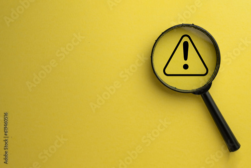 Attention sign,Exclamation mark,warning sign concept.,Magnifying glass focus on Hazard warning attention sign icon over yellow background with copyspace.