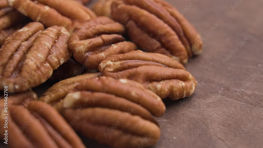Halved peeled pecan nuts closeup on wooden rustic surface. Dried healthy nutritious ingredient. Rotation Halved peeled pecan nuts closeup on wooden rustic surface. Dried healthy nutritious ingredient. Rotation