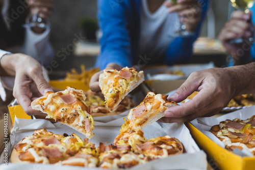 Colleague hands and friends eating pizza After a long meeting, They are having party at home office, eating pizza and having fun. leisure, food and drinks, people and holidays.