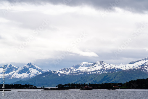A Norwegian fjord on a harsh overcast day, with dark fjords in the distance and white snow capped with a dramatic sky. © Rolands