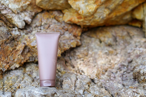 A brown tube of cosmetic cream or hair shampoo without label on the stones background with copy space. Mockup for cosmetic, moisturizer, mask or scrub