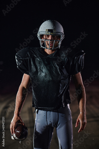 American Football Field  Lonely Athlete Warrior Standing on a Field Holds his Helmet and Ready to Play. Player Preparing to Run  Attack and Score Touchdown.
