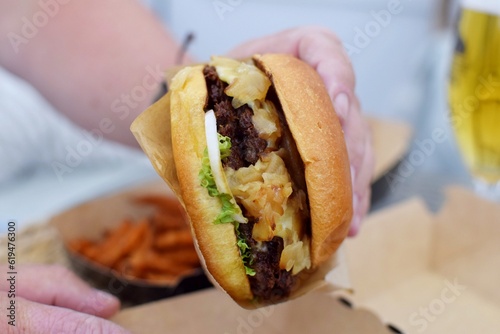 A man takes a burger out of the box, next to it are french fries .  Delivery of the product to the house.