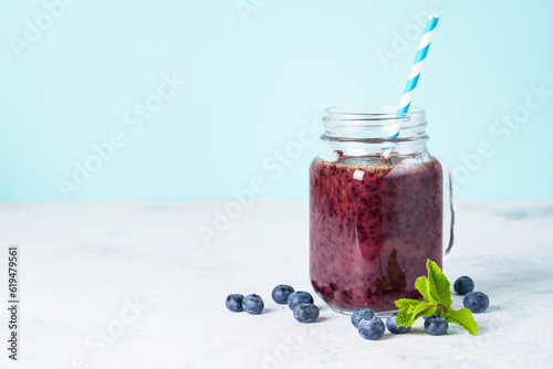 Blueberry smoothie with fresh berries at blue background.