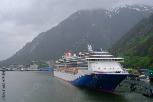 Modern cruiseship cruise ship liner Spirit docked at terminal in Juneau, Alaska during heavy rain and low cloud nature scenery with mountains and foggy misty atmosphere