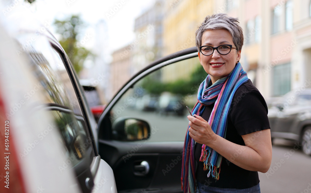 Smiling senior woman opens car door.