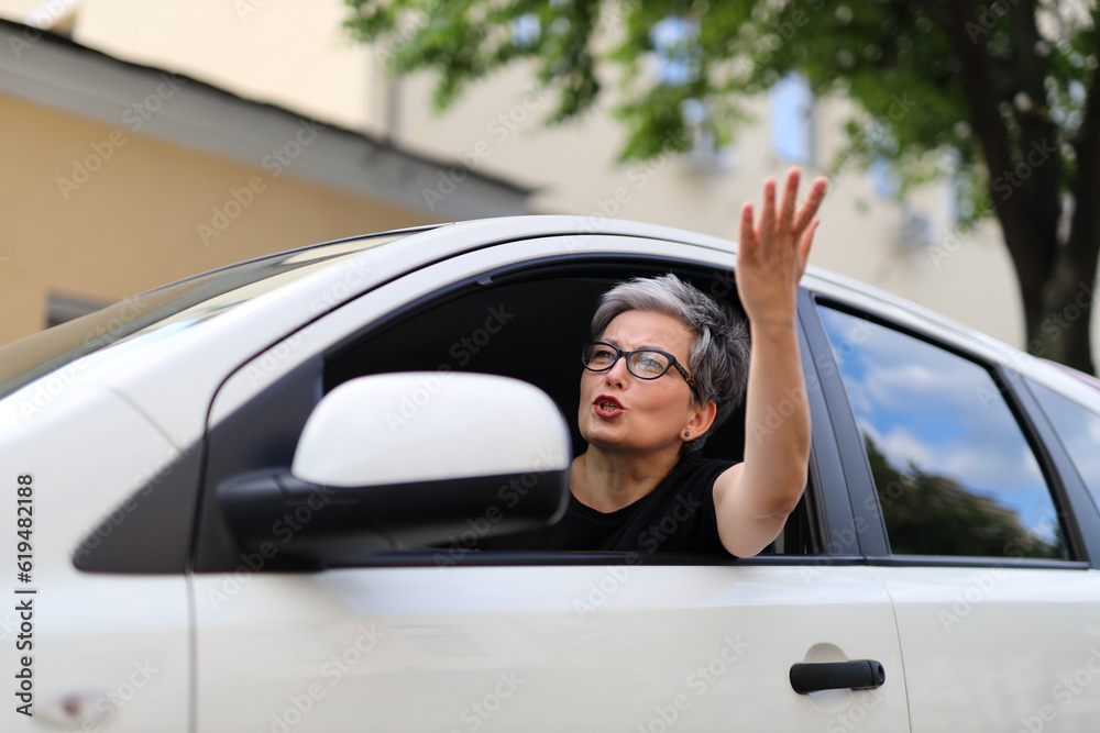 Angry and indignant woman waving from the car.