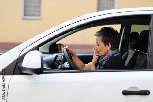 Tired senior woman yawns in the car. © Andrii Zastrozhnov