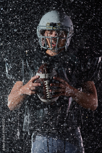 American Football Field  Lonely Athlete Warrior Standing on a Field Holds his Helmet and Ready to Play. Player Preparing to Run  Attack and Score Touchdown. Rainy Night with Dramatic Fog  Blue Light