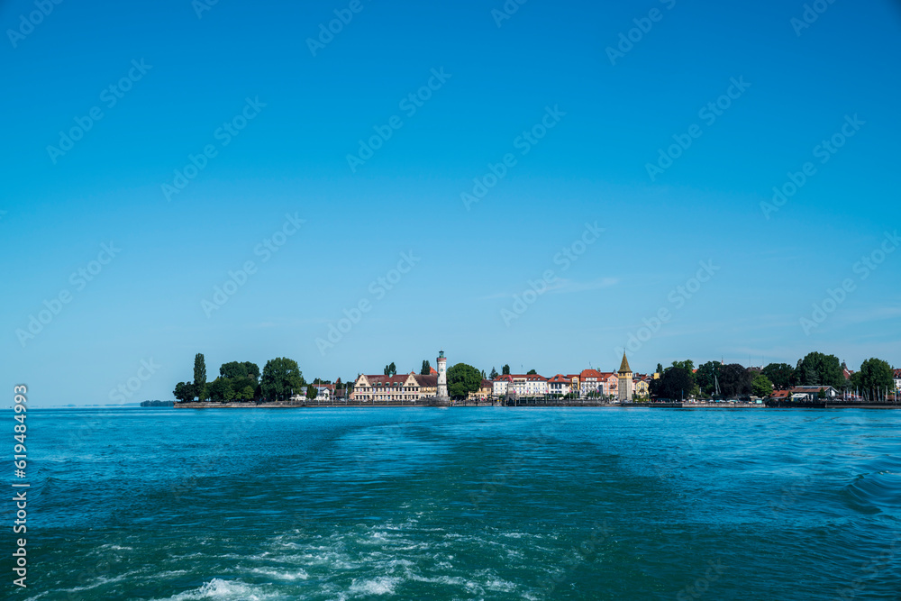 Germany, Bodensee lake constance, beautiful view on historical city of lindau island from ferry on the water in summer with blue sky and sun