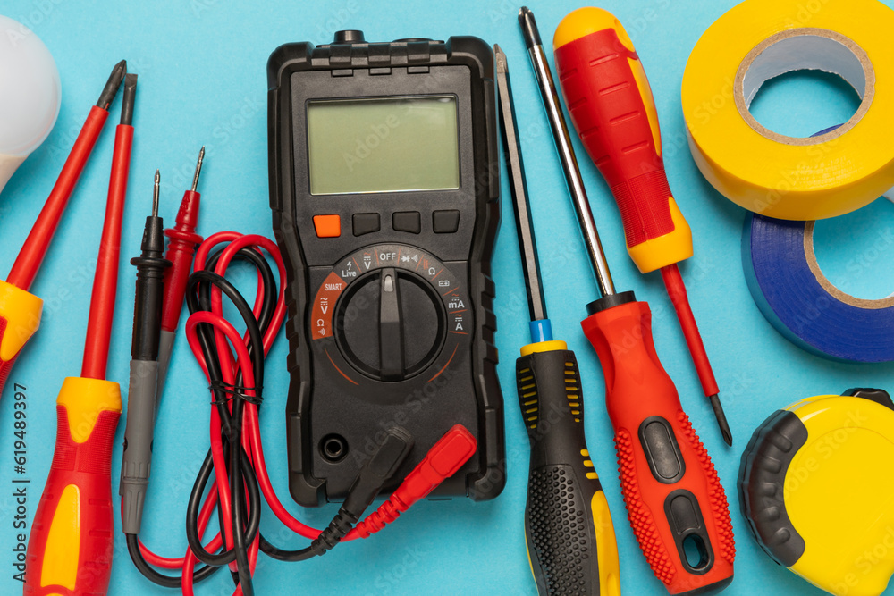 Electrician equipment on blue background with copy space.Top view.Electrician tool set.Multimeter, tester,screwdrivers,cutters,duct tape,lamps,tape measure and wires.Flet lay. Electrician equipment on blue background with copy space.Top view.Electrician tool set.Multimeter, tester,screwdrivers,cutters,duct tape,lamps,tape measure and wires.Flet lay.