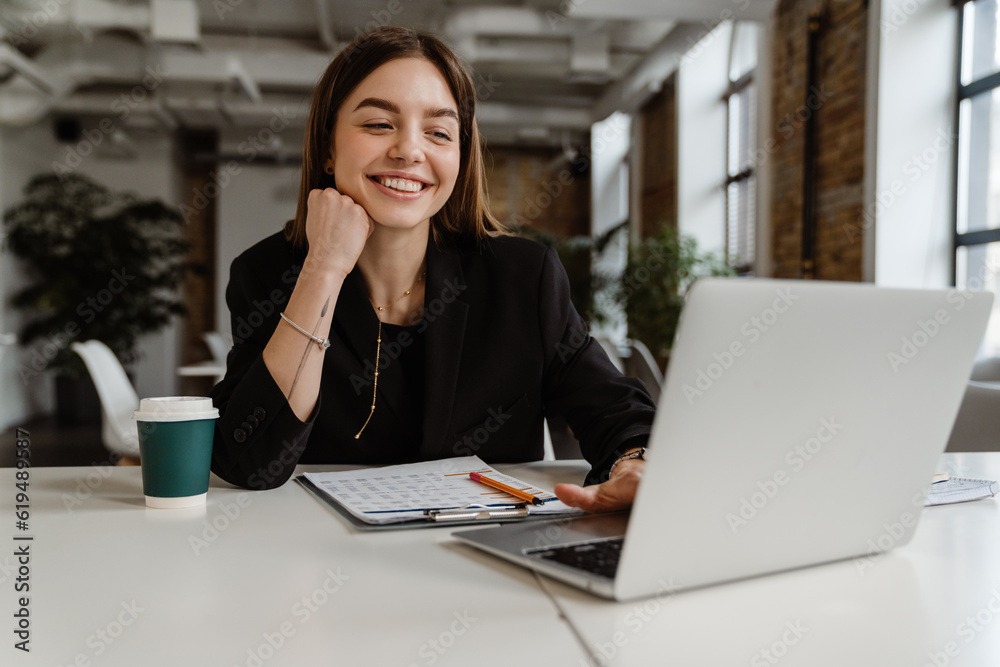 Cheerful business woman working on laptop in office Cheerful business woman working on laptop in office