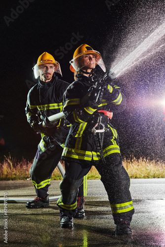 Fotografia Firefighters using a water hose to eliminate a fire hazard