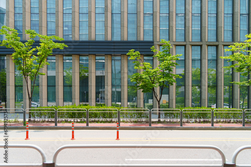 Road side view in front of a building with glass windows. A blocking fence is installed between the road and the sidewalk, making it difficult for pedestrians to jaywalk. photo