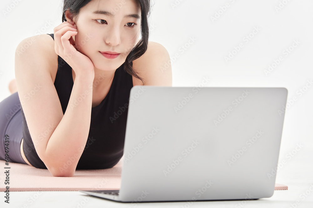 young woman doing home training while looking at her laptop young woman doing home training while looking at her laptop