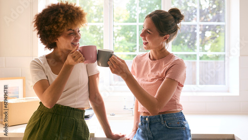 Two Female Friends Or Same Sex Couple Taking A Coffee Break From Unpacking On Moving Day In New Home