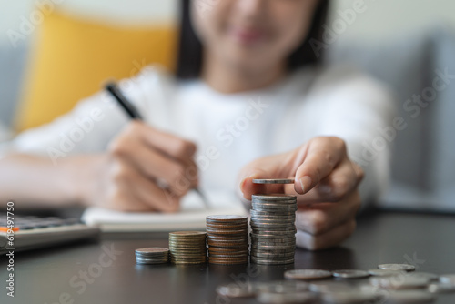 Close up hands of Woman putting coin into piggy bank house model saving for buy property