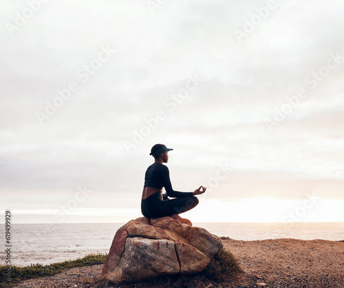 Lotus pose, woman and yoga at the beach, fitness and meditation with spiritual wellness in nature. Exercise, zen and female yogi on rock outdoor with holistic healing and calm, sea and mindfulness photo