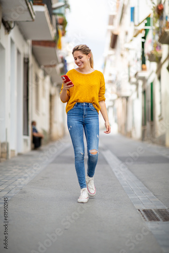 Smiling woman walking with phone in city