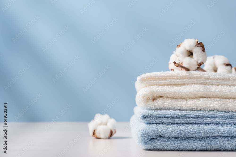 Stack of organic cotton terry towels on blue background with copy space. Delicate textiles, bath accessories Stack of organic cotton terry towels on blue background with copy space. Delicate textiles, bath accessories