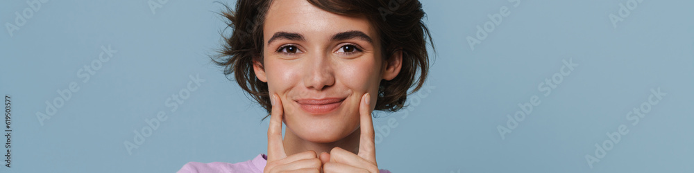 Obraz premium White excited woman wearing t-shirt pointing fingers at her cheek