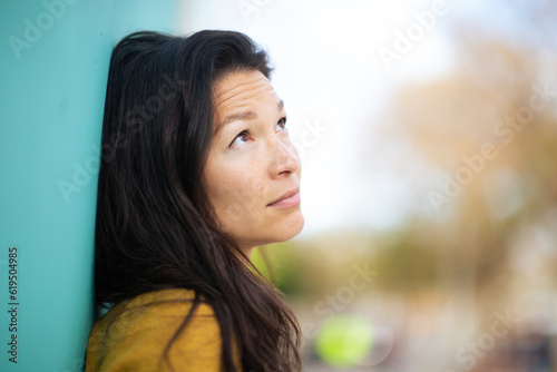 Upset young asian woman leaning to a wall outside