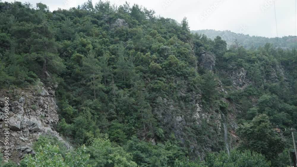 At the bottom of the gorge, with cliffs and mountains on either side, covered with trees, under cloudy weather. At the bottom of the gorge, with cliffs and mountains on either side, covered with trees, under cloudy weather.