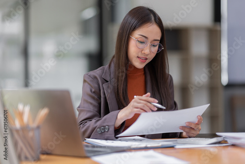  Asian business woman wear glasses or accountant working on calculator to calculate business data, accounting document and laptop computer at office, business concept