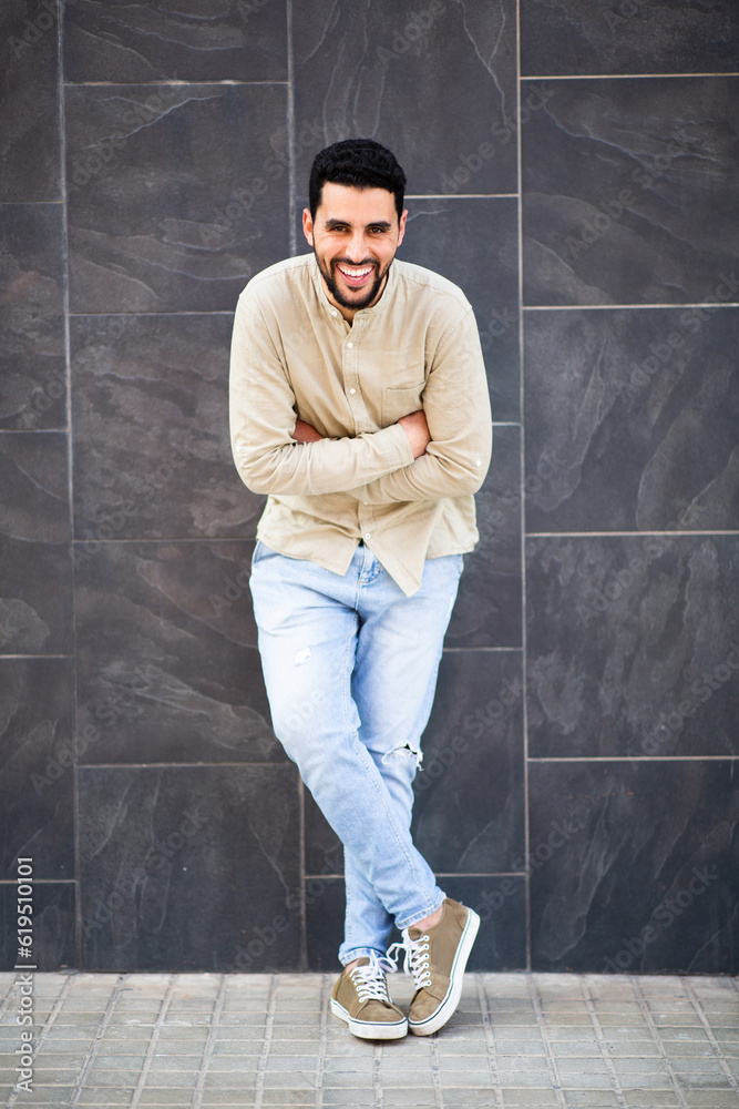 Smiling young arabic man standing against black wall Smiling young arabic man standing against black wall