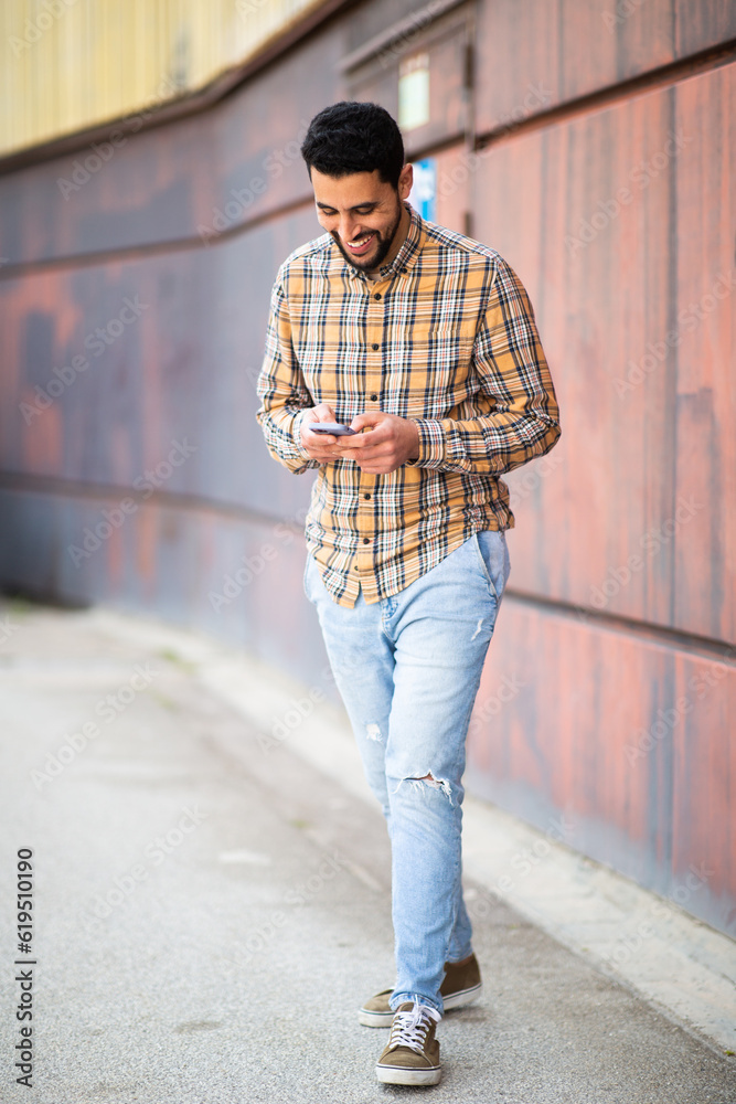 Young middle eastern man walking outside and using mobile phone Young middle eastern man walking outside and using mobile phone