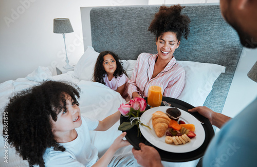 Happy family, mothers day and morning breakfast in bed for celebration, love and care together at home. Father and children giving mom food, meal or gift for start, holiday or weekend in the bedroom