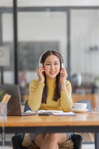 Wallpaper Mural Young adult happy smiling Asian student or business woman wearing headphones talking on online chat meeting using laptop in office or campus, asian female student wear glasses learning remotely. Torontodigital.ca