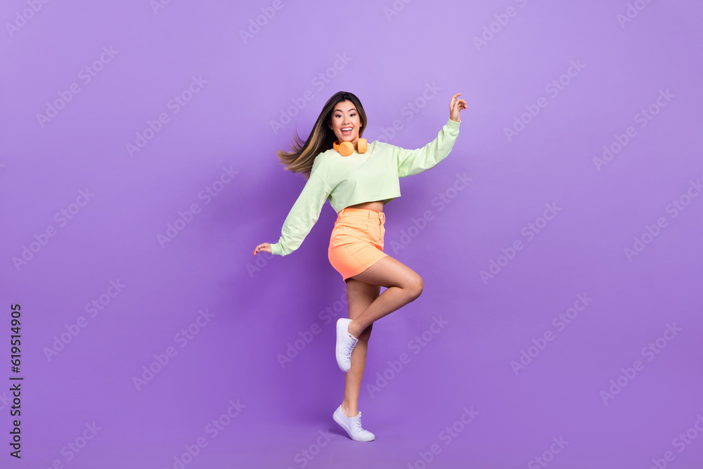 Full size photo of satisfied optimistic pretty woman dressed green shirt stylish skirt stand on tiptoe isolated on purple color background