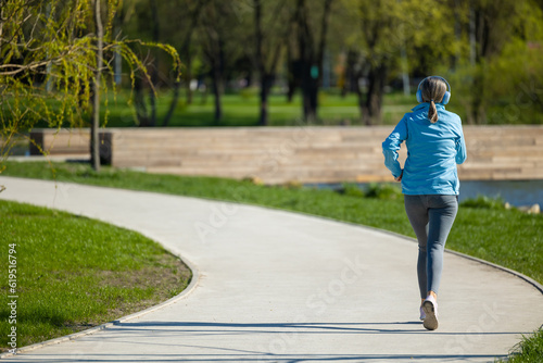 Woman in blue blazer listening to the music and jogging
