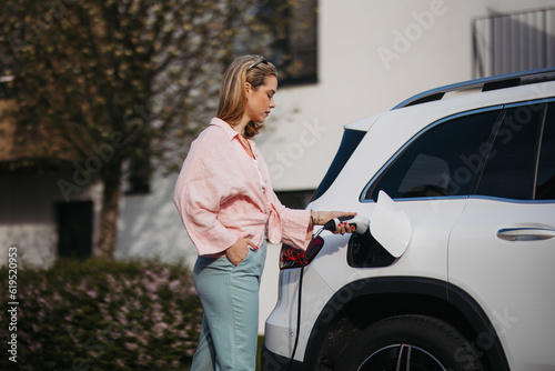 Woman charging her electric car, sustainable and economic transportation concept.