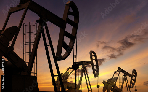 Fototapeta Naklejka Na Ścianę i Meble -  Oil pumps under a sunset sky. Fossil fuel issues and environmental concerns.