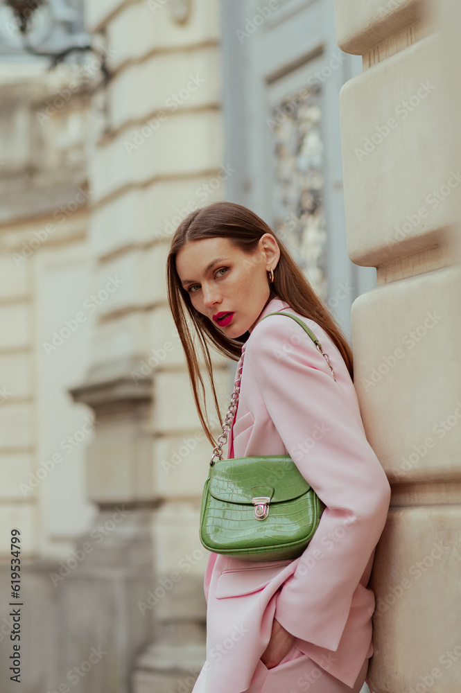 Fashionable elegant confident woman wearing trendy pink suit blazer, carrying green faux leather shoulder bag, posing in street. Outdoor fashion portrait Fashionable elegant confident woman wearing trendy pink suit blazer, carrying green faux leather shoulder bag, posing in street. Outdoor fashion portrait