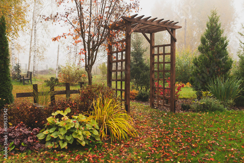 Photographie wooden rustic archway in autumn natural garden. Foggy october day