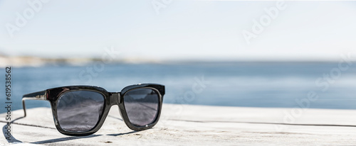 Sonnenbrille af einem Holzdeck an der Küste