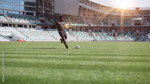 African American man playing football on the stadium field. A man runs with a soccer ball across the field. © Katsiaryna