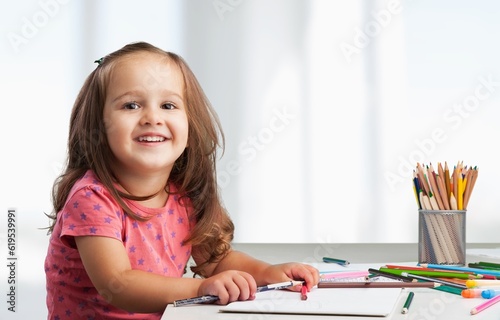 Cute small girl draws at a desk at home