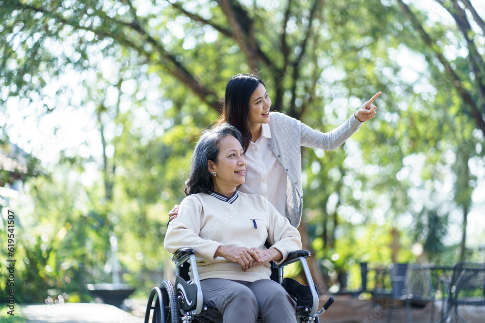 Asian senior woman in wheelchair with happy daughter. Family relationship retired woman sitting on wheelchair in the park age care at retirement home. Asian senior woman in wheelchair with happy daughter. Family relationship retired woman sitting on wheelchair in the park age care at retirement home.
