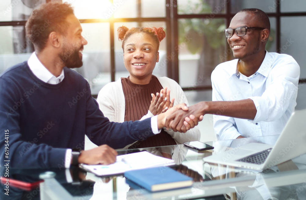 African american business team talking about strategy while looking at laptop, in office African american business team talking about strategy while looking at laptop, in office