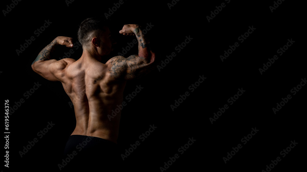 Horizontal banner, back view of male bodybuilder with developed body muscles, studio photo on black background.