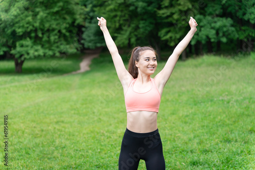 Young fit slim woman enjoying nature standing in green meadow starting morning exercicing