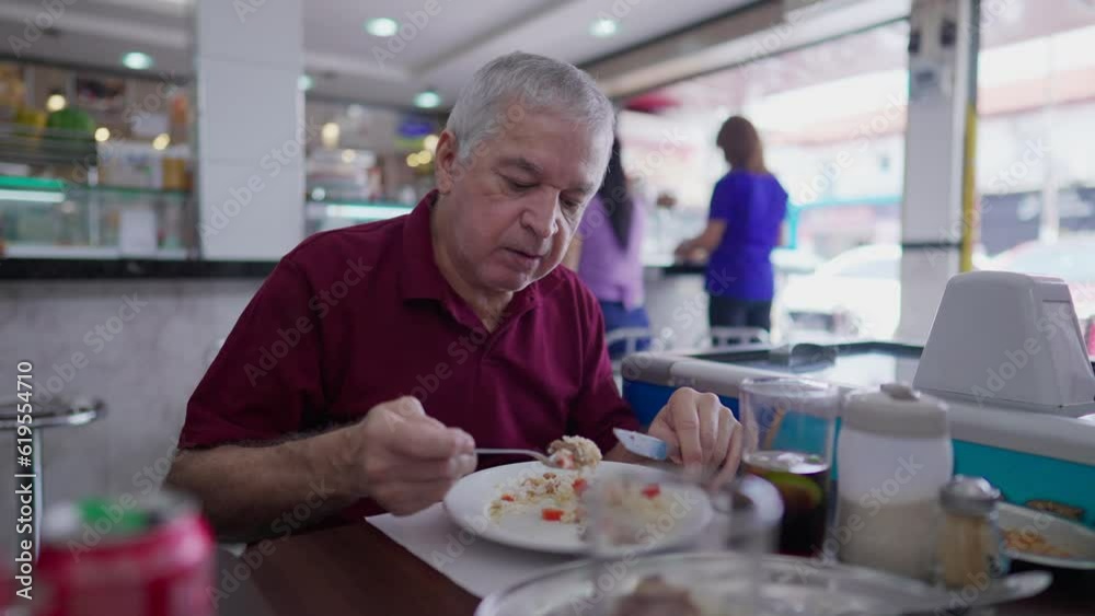 Senior man eating lunch in traditional Brazilian cafeteria. One casual Caucasian Older person eats food meal at restaurant Senior man eating lunch in traditional Brazilian cafeteria. One casual Caucasian Older person eats food meal at restaurant